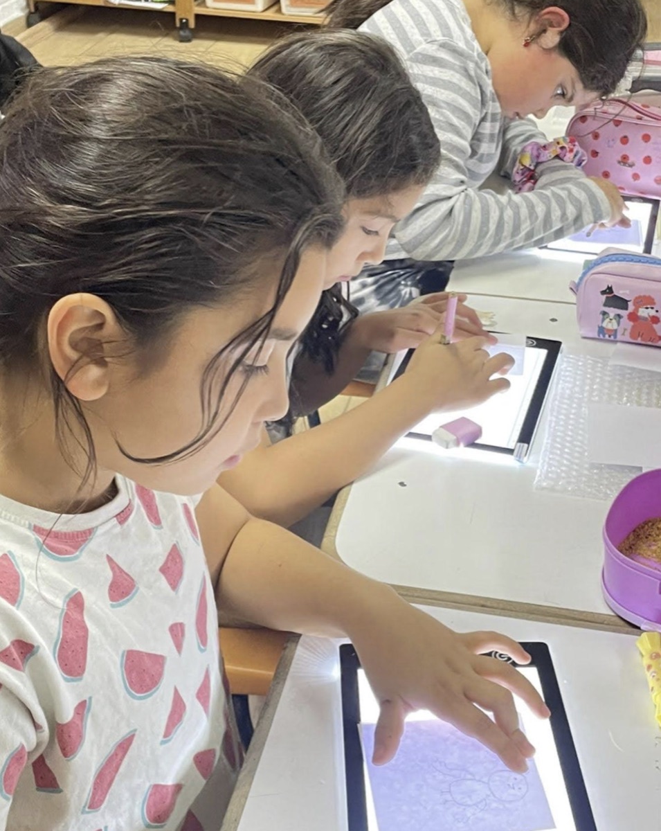 Niñas dibujando sobre mesas de luz